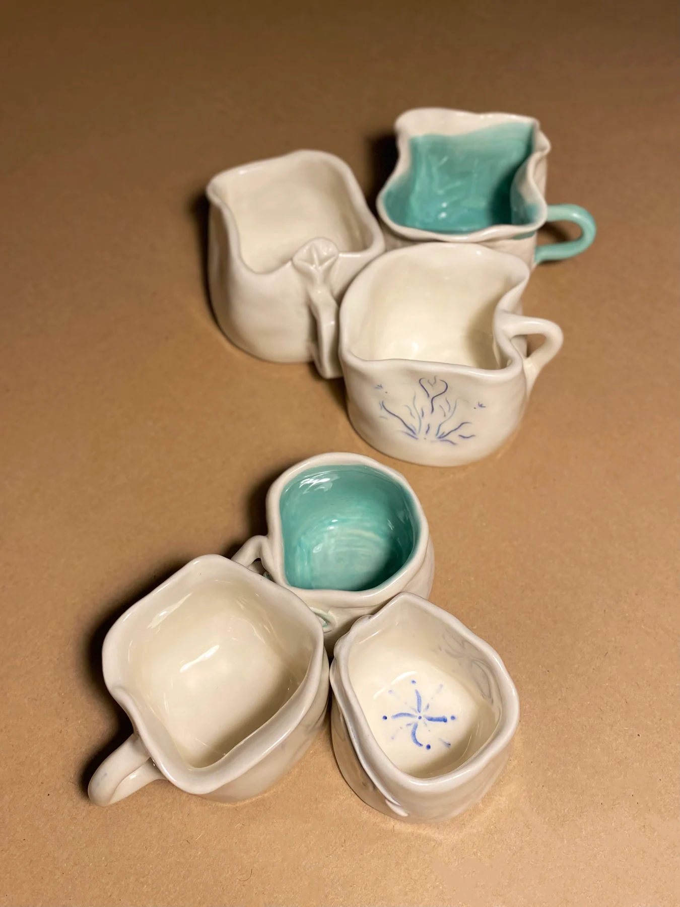 Handbuilt mugs with botanical details and colourful interiors