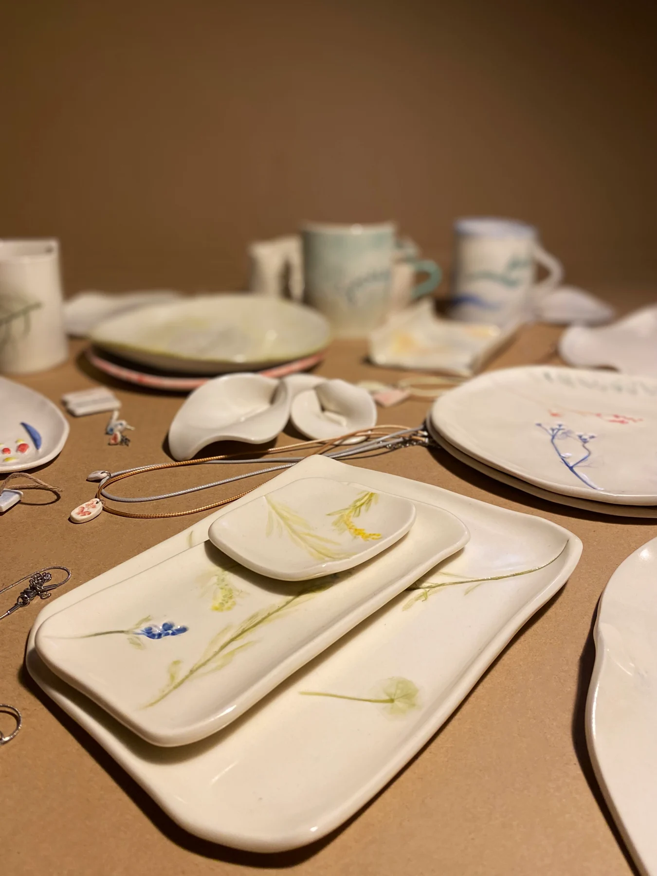 An arrangement of handmade mugs, plates and ceramic jewelry